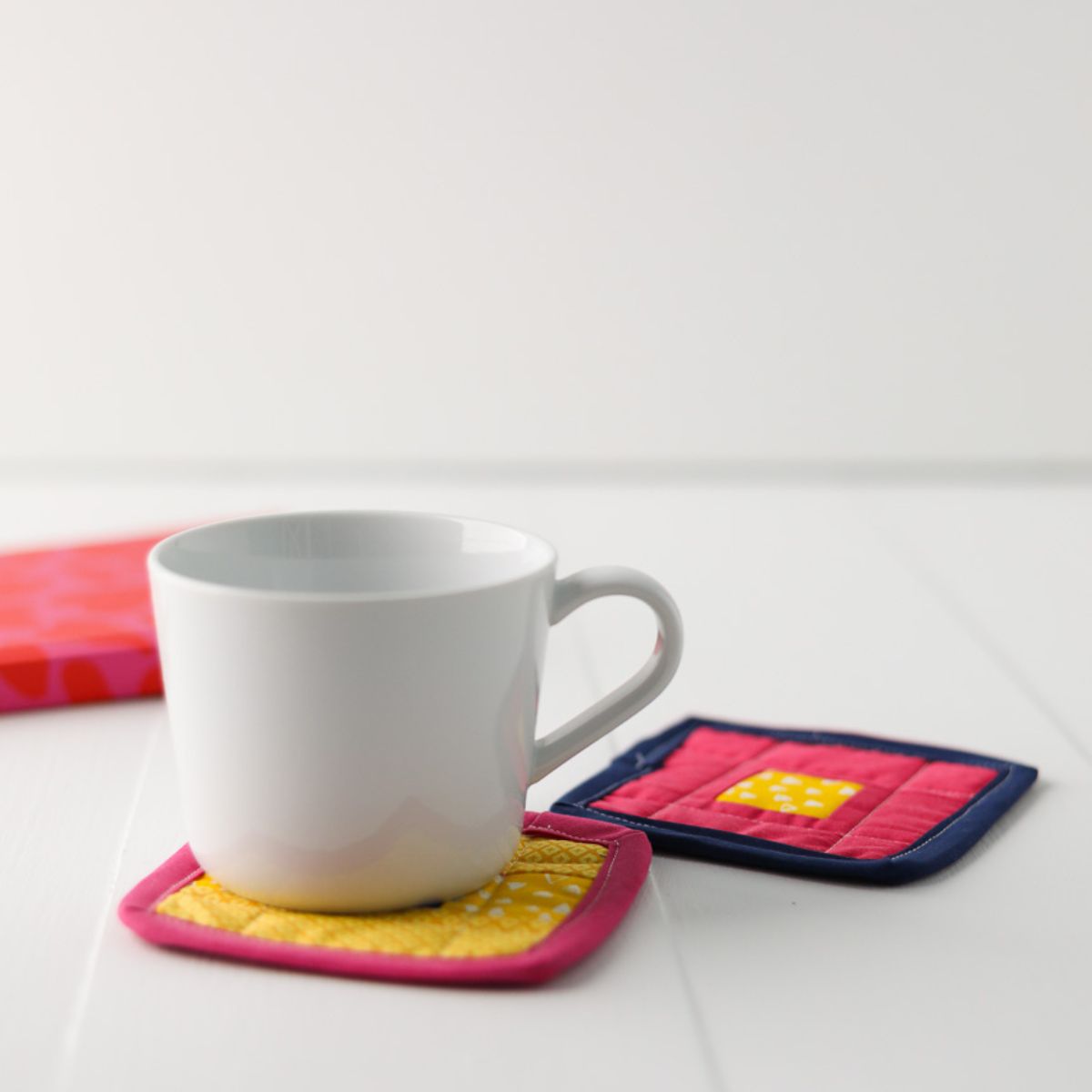 white coffee cup sitting on patchwork coasters