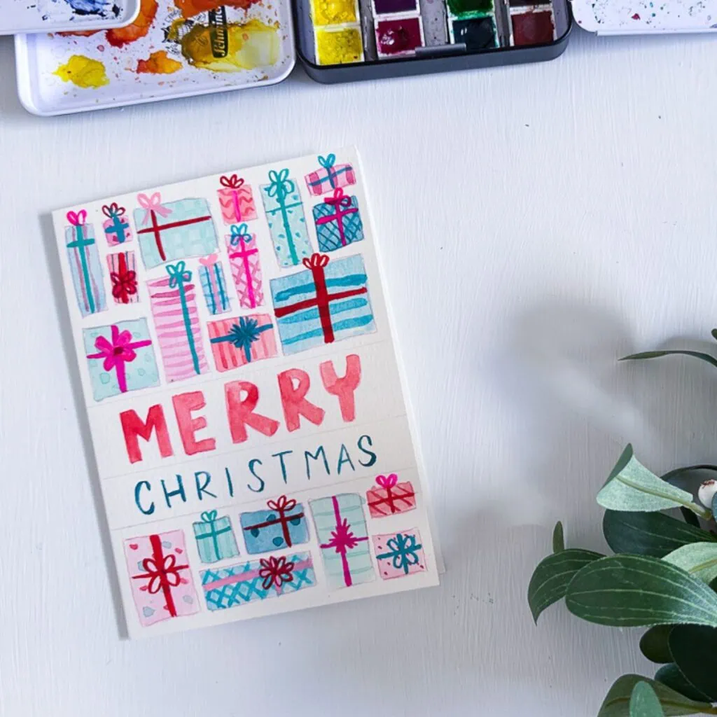 card with watercolor presents and hand lettering that says Merry Christmas