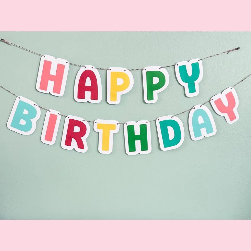 Happy birthday banner made with colorful paper on an aqua wall.