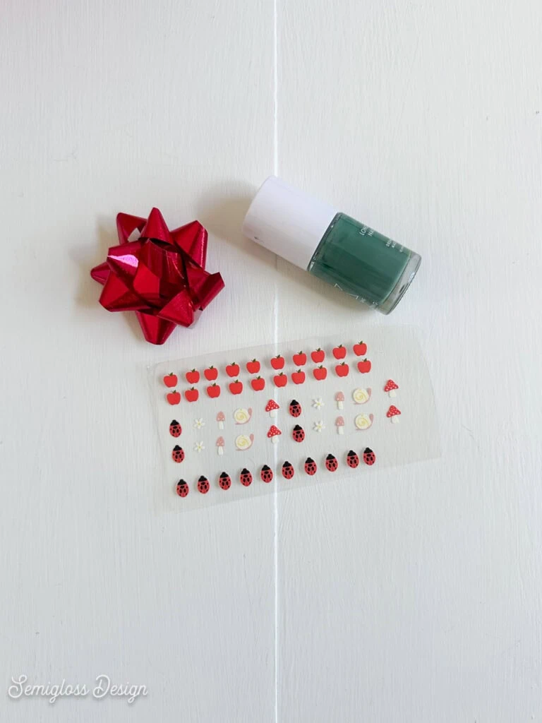 uv dtf printed nail decals, nail polish and a Christmas bow