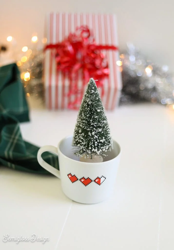 mug with pixel heart design in front of present and lights